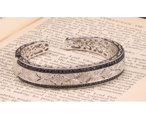 A Macy &amp; Co Art Deco style silver, diamond and sapphire hinged cuff bracelet, the filigree shank engraved with scrolling 