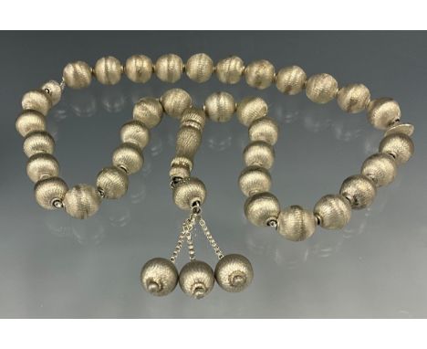 A single stand of textured globular silver worry beads, triple tassel terminal, unmarked, purchased in the United Arab Emirat