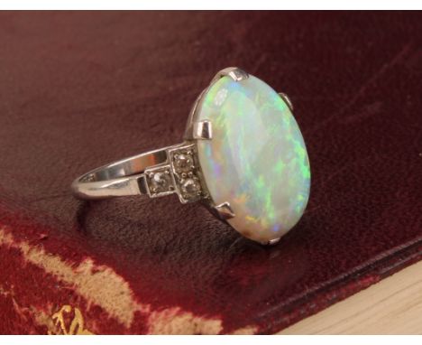 An Art Deco platinum ring, the central large claw set polished opal cabochon, flanked to either side by three single cut diam