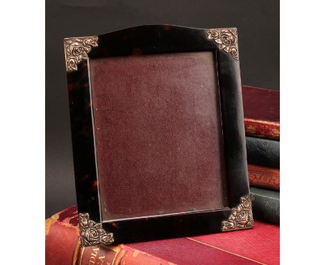 An early 20th century silver coloured metal mounted tortoiseshell easel photograph frame, serpentine cresting, brackets to an