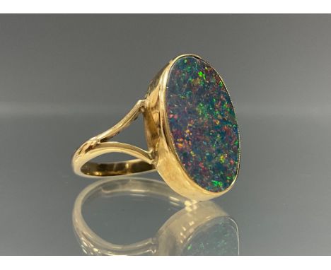 A black opal ring, oval opal with strong black, green, red, orange and blue colour play, rollover collar, 9ct gold shank, sta