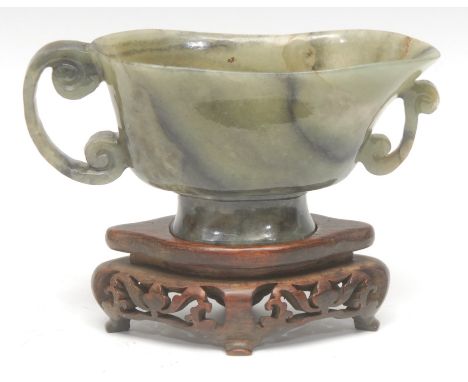 A Chinese export-ware jade libation vessel on stand, C-scroll handle, the hardwood stand pierced with floral motifs and stand