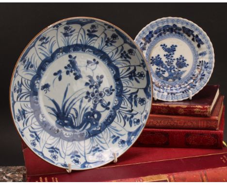 An early 18th century Chinese circular dish, painted in tones of underglaze blue with flowers and rockwork, later clobbered i