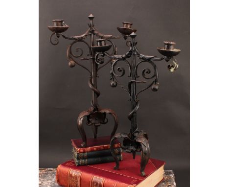 A pair of Arts and Crafts wrought iron two-light candelabra, the each pillar entwined with a serpent reaching for an apple, i