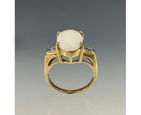 An opal and diamond ring, central oval creamy white opal with green, blue, red and violet play, between two stone diamond acc