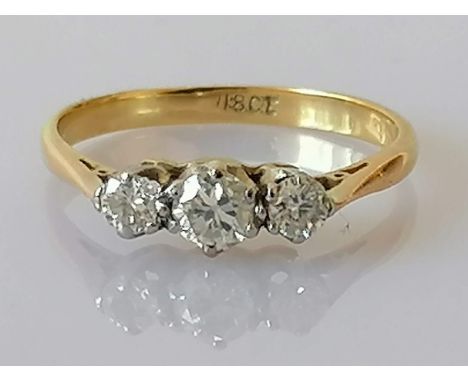 A graduated three-stone diamond ring on a yellow gold setting, size L, the central round-cut diamond approximately 0.20 carat