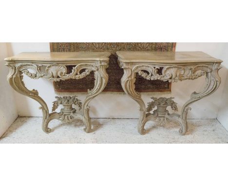 CONSOLE TABLES, a pair, 19th century French limed oak with serpentine tops on elaborately carved bases with shell and flower 