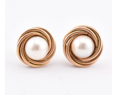 A pair of 14ct gold and pearl stud earrings. The 14ct yellow gold ring set with a single round pearl within a twisted border 