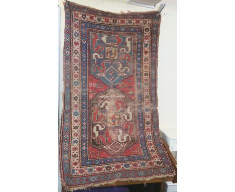 A red ground Caucasian rug with geometric designs, 200cm x 122cm Condition Report:A heavily worn item with multiple rips, low