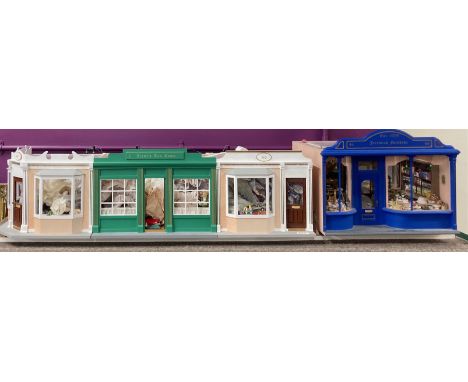 A handmade row of dolls house scale shops, W. 153cm. H. 36cm. With contents.