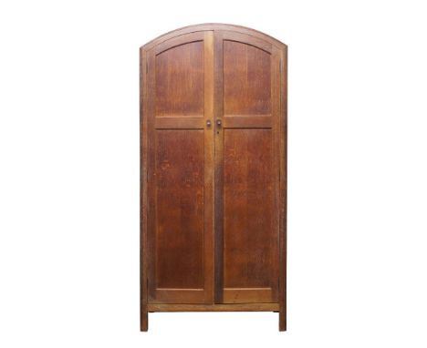 Heal's (British), a limed oak cupboard,c.1920, ivorine label to inner door – ‘Heal & Son Ltd London W’,Of arched form with tw