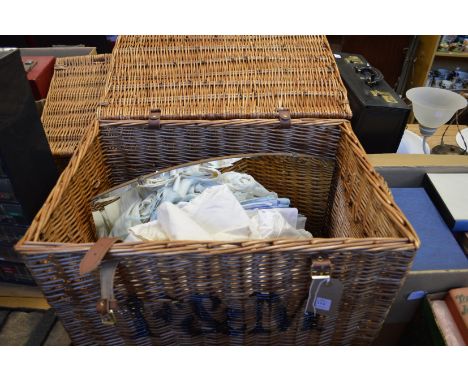 A Fortnum &amp; Mason wicker hamper containing linen and a mirror.