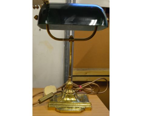 A brass desk lamp with green glass shade.