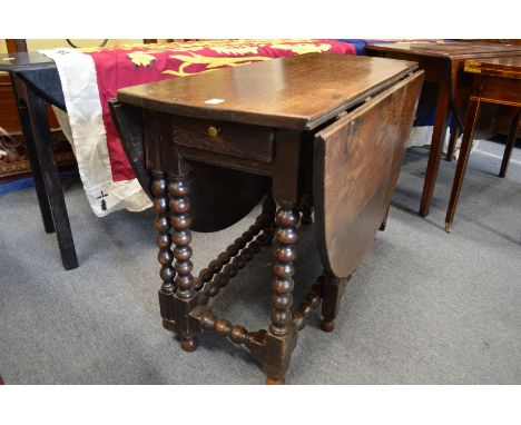 An 18th century oak oval drop-leaf, gate-leg dining table with bobbin turned supports.