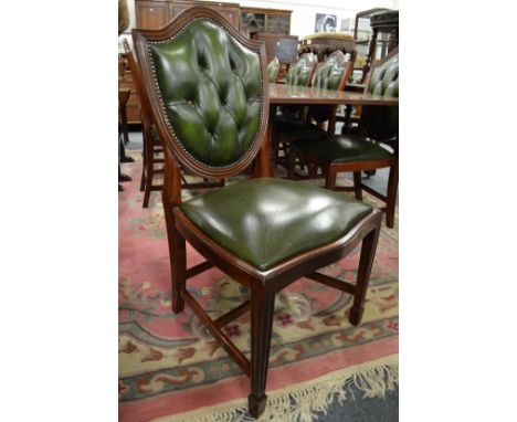A set of eight mahogany and leather upholstered shield back dining chairs with button upholstered backs and drop-in seats.