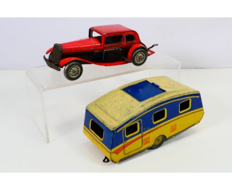 Mettoy - A vintage Mettoy (Gt Britain) clock work tin plate saloon car in two tone of red and black, pulling a caravan. Car c