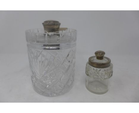 A cut glass silver topped decanter together with one other silver collared cut glass table jar 