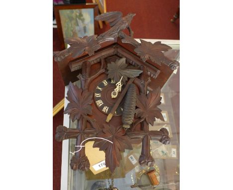 A 20th century German cuckoo clock, brass movement, Roman dial, with carved leaf decoration and bird finial, H.43cm (a/f) 