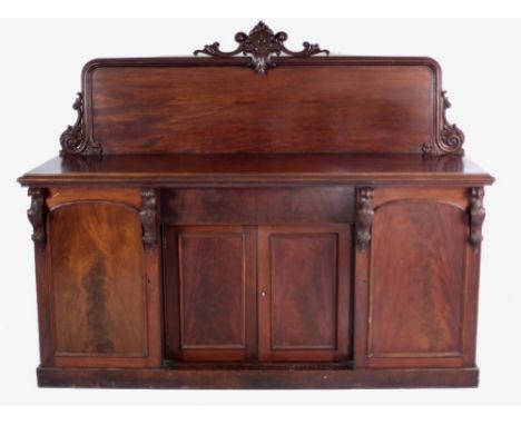 A Victorian Irish mahogany Sideboard, the plain rectangular figured mahogany back with carved capital sides, the moulded top 