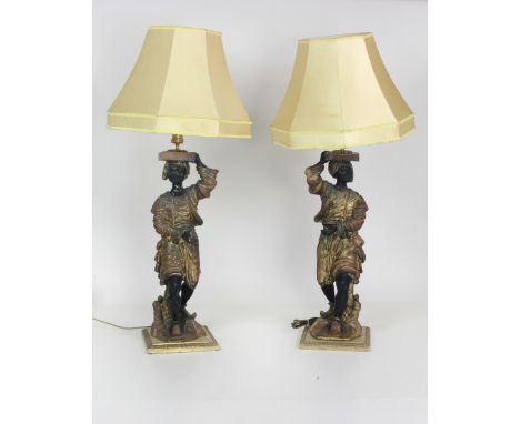 A pair of 19th Century Blackamoor figural Lamp Standards, on heavy moulded brass bases, each highlighted in gilt, with cream 