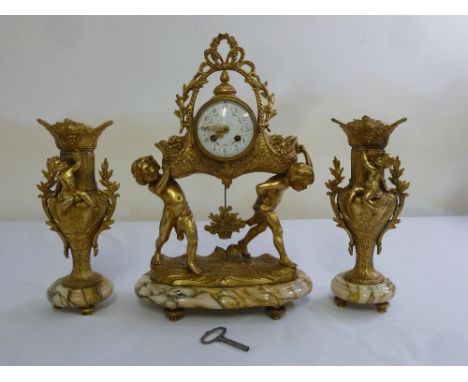 A gilt metal French style mantle clock set, the central dial supported by two putti all on marble bases