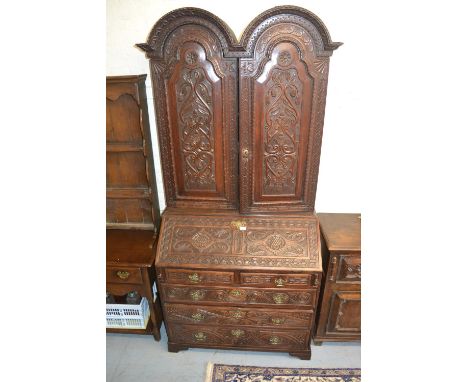 Carved oak bureau bookcase with a double dome two door top, above fall front enclosing fitted interior with two short and thr