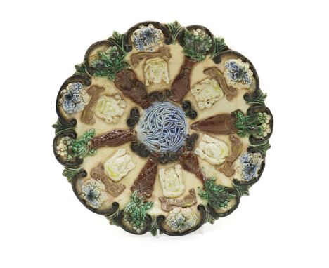 A Castle Hedingham pottery dish,designed and made by Edward Bingham, with raised masks each with a scroll bearing legends of 