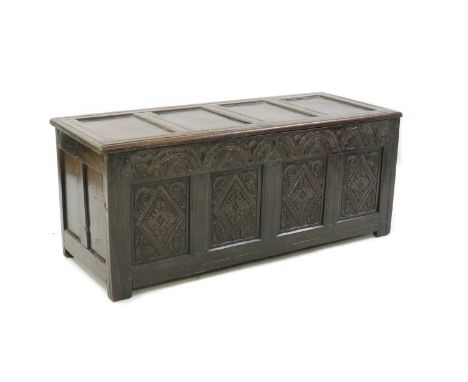 An oak coffer,17th century, the four panelled top over a profusely carved four-panel front and twin-panelled sides,142cm wide