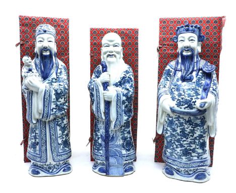 A collection of three Chinese blue and white house gods, 20th century, of 'Lu', 'Fu' and 'Shou' wearing a long robe decorated