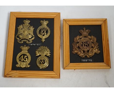 Five military helmet and shako plates mounted on two boards, including; the Nottinghamshire Regiment, the 2nd Staffordshire R