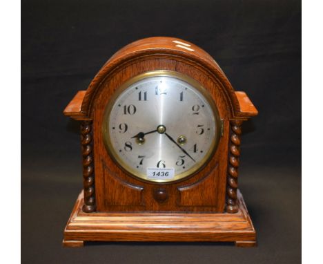 A dome top oak mantel clock, silvered dial, Arabic numerals, flanked by barley twist columns.