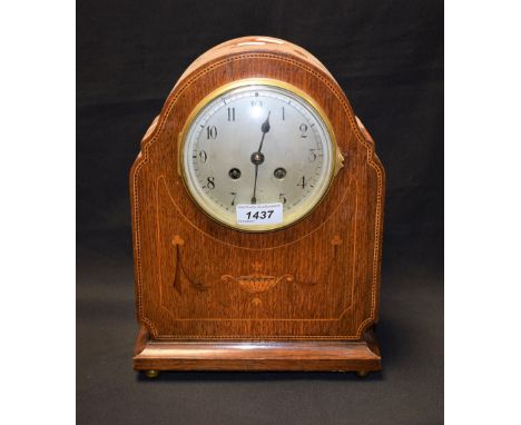 An Edwardian oak mantel clock, arched top, silvered dial, Arabic numerals, the case inlaidwith satinwood trophy and stringing