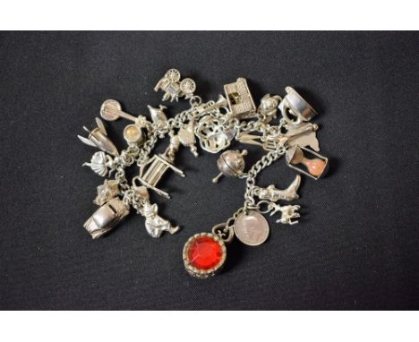 A silver bracelet with a variety of charms to include a car, mangle, steam engine; etc 