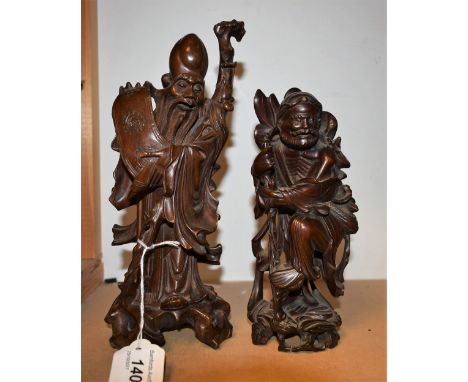 A 19th century Chinese hardwood carving, of Shou Lao, the elderly sage unfolds a scroll of wisdom, wearing flowing robes, his