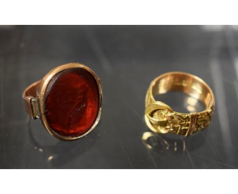 An 18ct gold buckle ring, 7g; a carved signet ring, rose gold frame, unmarked (2)  