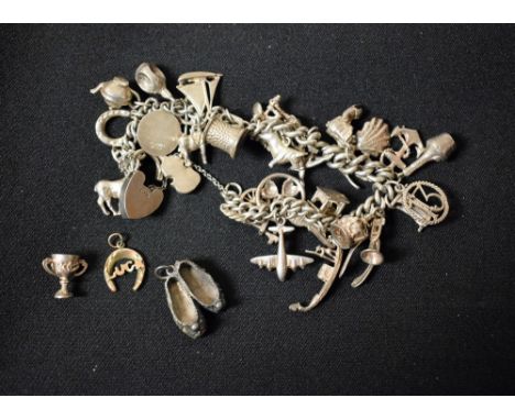 A silver charm bracelet suspending approx 30 charms inc Horse, Tankard, Stag, Aeroplane, Violin, teapot etc, part unmarked, p