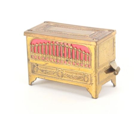 A gilt brass finish novelty tape measure in the form of a chamber organ, playing a ñtuneî as the tape is re-wound, 5.5cm