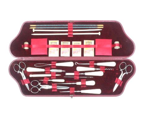 An early 20th Century red leather covered sewing companion of swept and rectangular form, the maroon velvet lined interior wi