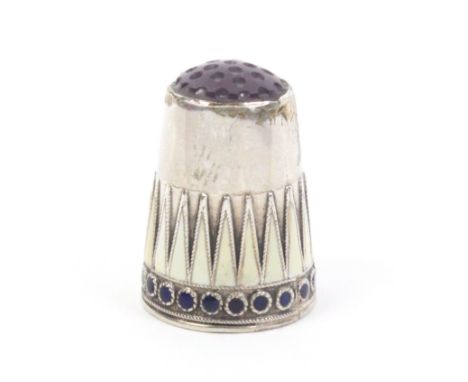 A good silver and enamel Norwegian thimble, amethyst coloured top, over a frieze of cream enamel van dykes and a blue dot ena