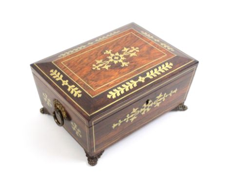 A Regency rosewood sewing box of sarcophagal form inlaid to the lid, front and sides with cut brass leaf and flower motifs an