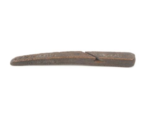 An early 19th Century wooden knitting stick of square sections, tapering and curved form carved to all four faces with geomet