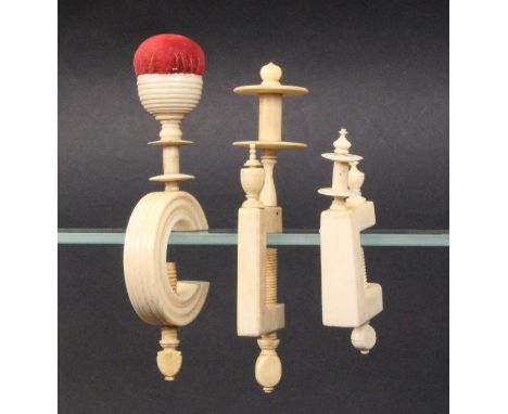 Three 19th Century ivory sewing clamps comprising a turned ïCÍ frame example below a reel and cup form pincushion, 14cm high,