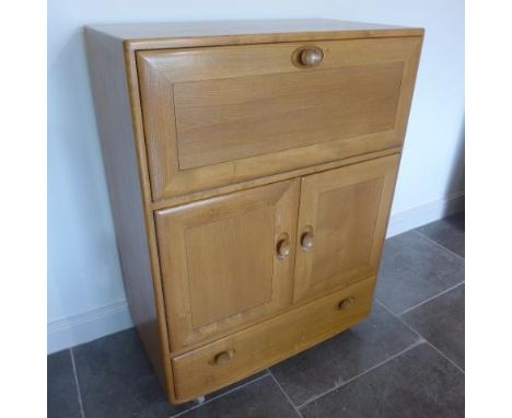 An Ercol Golden Dawn blonde elm cabinet with a drop down front above two cupboard doors and a base drawer - Height 110cm x 83