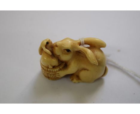 A Japanese carved ivory netsuke, carved as a hare and leveret, each with inset eyes, signed to the base, 4cm wide.    Conditi