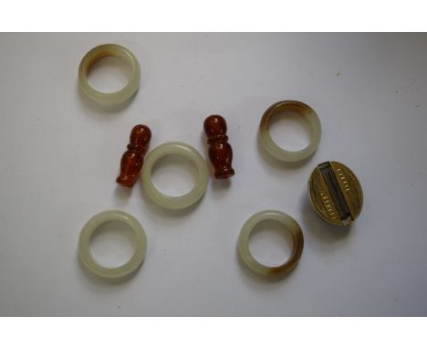 A set of five Chinese celdon and russet jade rings; together with two amber beads; and another white metal item. 