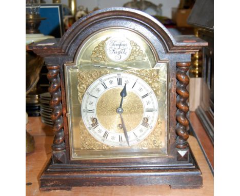 A 1920s oak cased mantel clock having an arched brass dial with silvered chapter ring and Roman numerals, eight day chiming m