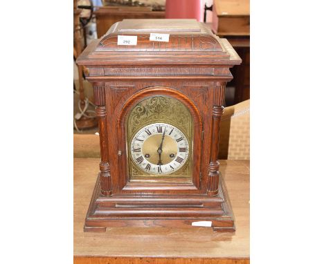 Junghans, an early 20th Century mantel clock set in an oak case of architectural style with arched brass face and a brass mov