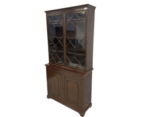 Early 20th century Georgian design mahogany bookcase on cupboard, dentil cornice over astragal glazed doors enclosing adjusta