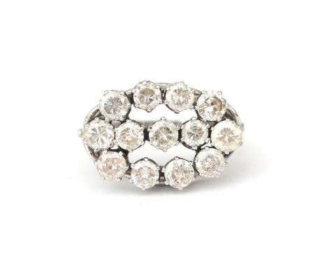 A 14 karat white gold diamond cluster ring. Set with three brilliant cut diamonds in the center, surrounded by ten brilliant 