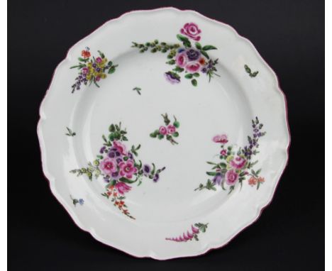 A mid 18th century English porcelain plate, possibly Worcester, painted with floral bouquets and springs within a red border,